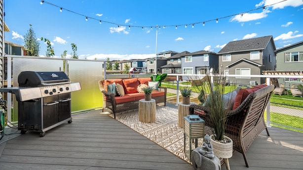Une terrasse avec un barbecue, du mobilier d’extérieur et une vue sur les maisons voisines.