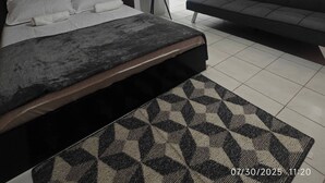 A bedroom with a bed, a sofa, a painting, and a vase with dried flowers. - Escape to LuxHomme Your Spacious Sanctuary in the Heart of Baguio (Baguio)