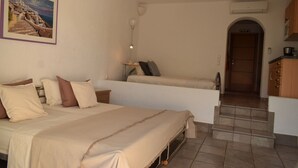 A bedroom with a bed, bedside tables, a lamp, a painting, and a view of a staircase leading to a door.