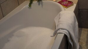 A bathtub with a towel, a book, and a candle.