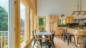 Eine moderne Küche mit Holzschränken, einer Marmorarbeitsplatte und einem Essbereich mit Tisch und Stühlen.