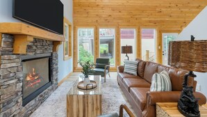Ein gemütliches Wohnzimmer mit Kamin aus Stein, Holzboden und braunem Ledersofa.