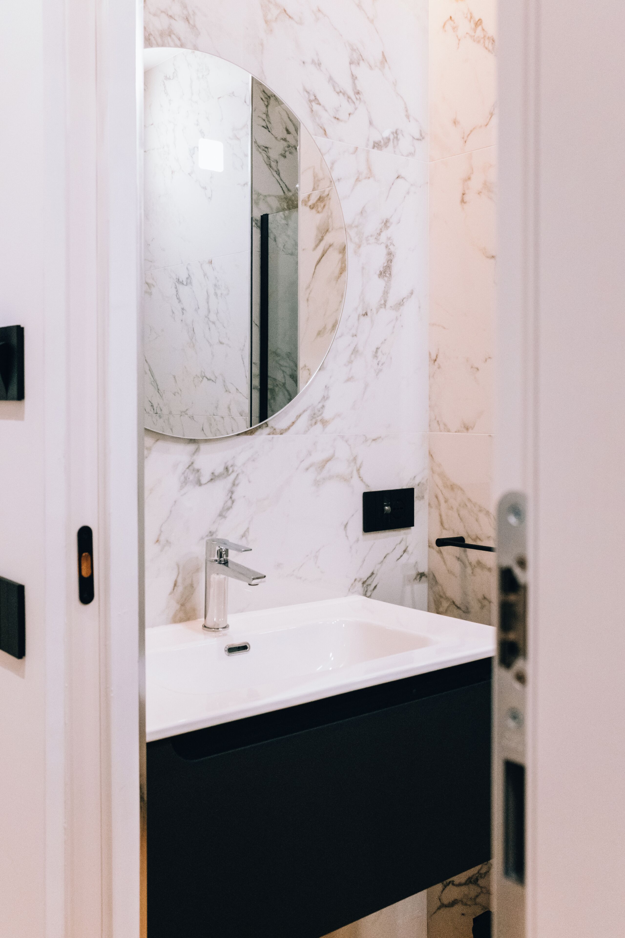 A bathroom with a white sink, a mirror, and marble walls.