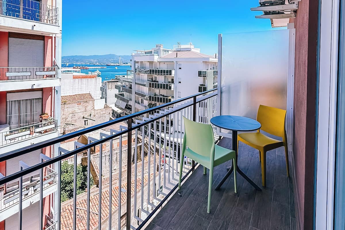 Un balcón con vistas al mar, una mesa con sillas y una barandilla.
