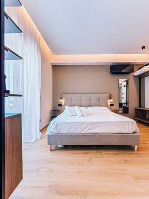 A modern bedroom with a large bed, bedside tables, a mirror, and a wooden floor.