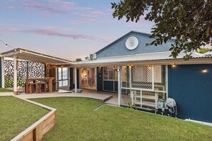 Moderni talo, jossa on katettu terassi, aidattu takapiha ja suuri ikkuna, josta on näkymä pihalle.