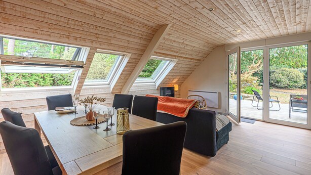 Un comedor amplio con una mesa y sillas de madera, ventanas grandes y vistas al exterior.
