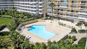 A hotel with a swimming pool surrounded by palm trees and greenery.