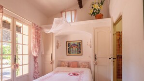 A bedroom with a bed, a window with curtains, a door, and a shower area. - Font Mourier by Interhome (Cogolin)