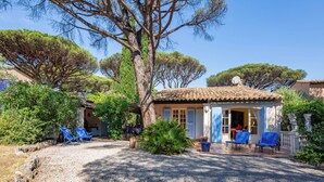 A rustic villa with a tiled roof, a gravel driveway, and a seating area with blue chairs. - Font Mourier by Interhome (Cogolin)