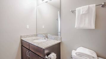 A bathroom with a granite countertop sink, a dark wood cabinet, a toilet, and a towel hanging on a towel rack.