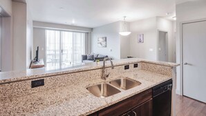 A modern kitchen with granite countertops, stainless steel sink, and built-in dishwasher.