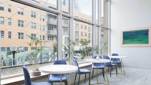 A modern office with large windows, blue chairs, and a white table.