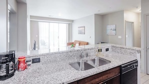 A modern kitchen with granite countertops, a double sink, and a dishwasher.