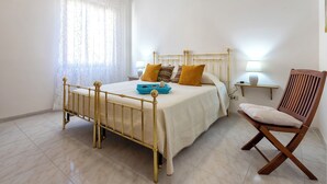 Une chambre à coucher avec un lit, des tables de chevet, une chaise et une fenêtre avec des rideaux.