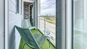 A balcony with two green chairs, a patterned wall, and a view of a cityscape. - L'écume by Interhome (Pornic)