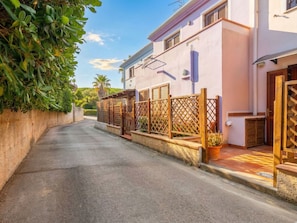 Une rue étroite, bordée de maisons des deux côtés, avec des clôtures en bois et un ciel dégagé.