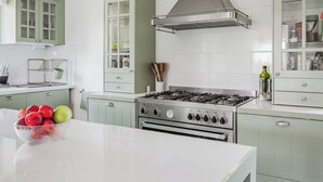 Uma cozinha com fogão a gás, forno e uma tigela de frutas no balcão.