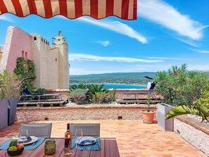 Un espace extérieur aménagé pour prendre les repas, avec vue sur la mer et les collines.