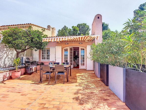 Un patio con una mesa y sillas, una planta en maceta y vistas de un edificio con torre.