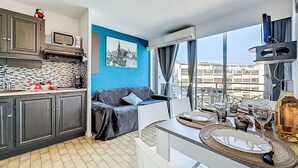 Una cocina moderna con armarios grises, una pared de acento azul y una zona de comedor con una mesa preparada para dos.