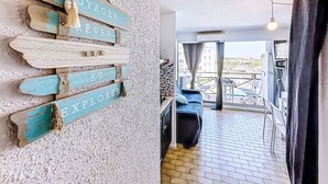 Un balcón con vistas a la ciudad, una zona de estar con sofá y mesa, y una pared con letreros de madera.