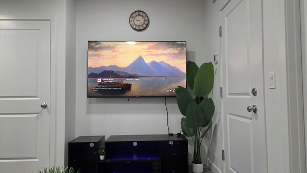 Ein an der Wand befestigtes Fernsehgerät zeigt eine Landschaft mit Bergen und einem Gewässer.