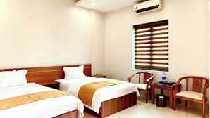 A hotel room with two beds, a desk, a chair, and an air conditioning unit. - Sunshine Hotel BN (Vo Cuong)