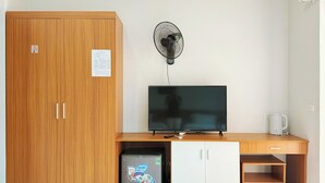 A compact room with a wooden wardrobe, a small fridge, a TV, a fan, and a coffee maker. - Sunshine Hotel BN (Vo Cuong)