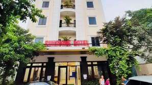 A multi-story hotel with a prominent red sign, balconies, and parked cars in front. - Sunshine Hotel BN (Vo Cuong)