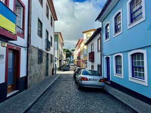 Eine enge Kopfsteinpflasterstraße gesäumt von bunten Häusern, ein geparktes Auto und ein Verbotsschild.
