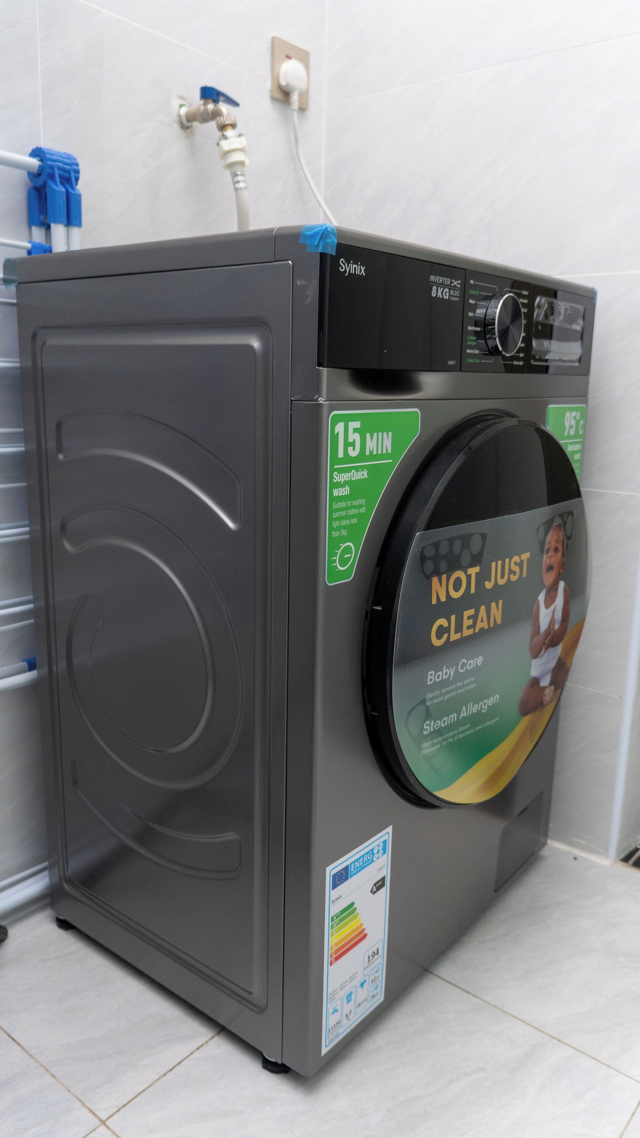 A front-loading washing machine with a 15-minute SuperQuick wash cycle and a Baby Care detergent label.