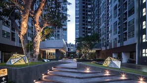 A modern high-rise building with a central courtyard, large trees, and a well-lit entrance area. - Pattaya Central - Best Pool (Pattaya)