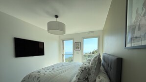 Une chambre à coucher avec un lit, un téléviseur fixé au mur et une fenêtre donnant sur un beau paysage.
