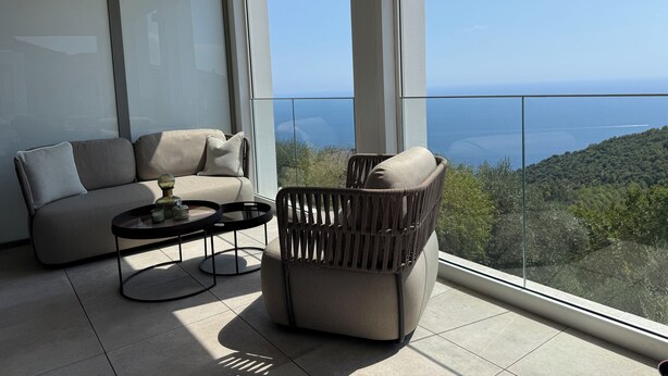Un balcon agrémenté d’un canapé, d’une chaise et d’une petite table, offrant une vue sur un paysage pittoresque.