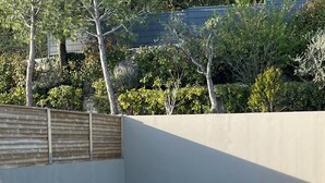 Une piscine rectangulaire avec un escalier en métal sur un de ses côtés, entourée d’une terrasse carrelée.