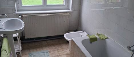 Un baño con ventana, lavabo, bidé y bañera.