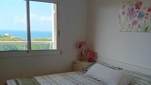 Ein Schlafzimmer mit einem Bett, einem Nachttisch, einem Fenster und einem Bild.