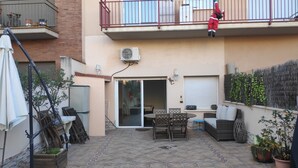 A patio area with a table and chairs, a sliding glass door, and a balcony with a railing.