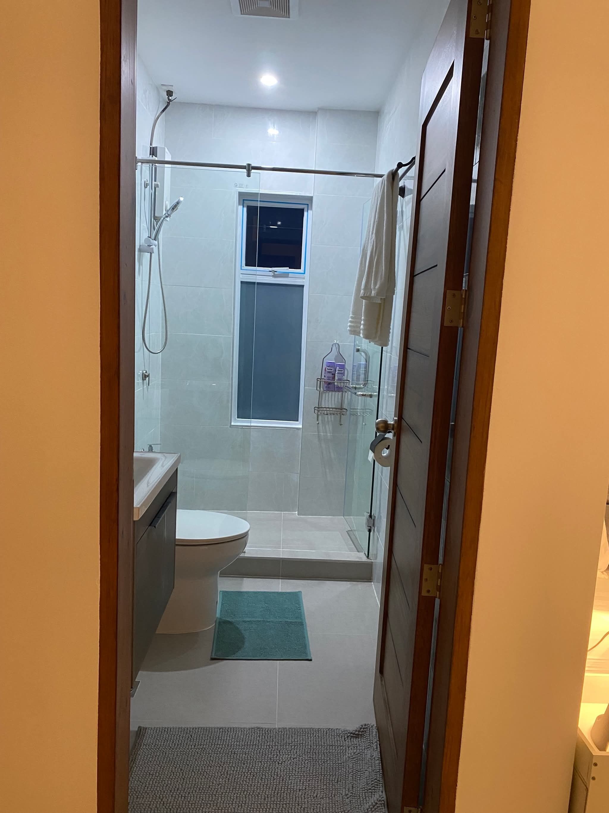 A modern bathroom with a glass shower enclosure, a toilet, and a sink.