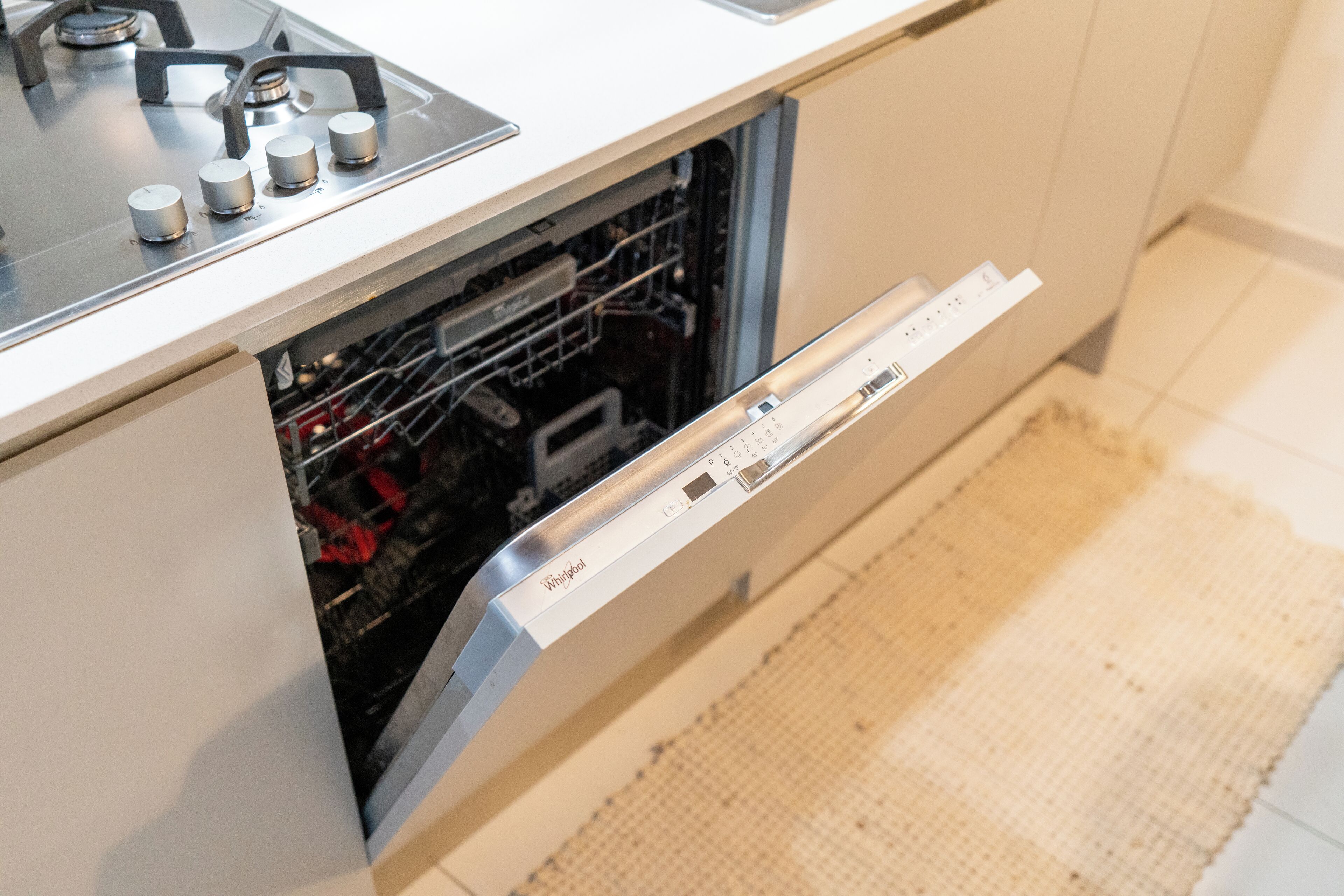 A kitchen with a dishwasher, stove, and a control panel.
