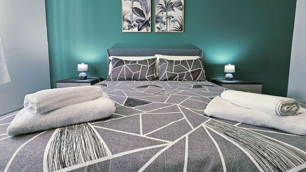 Habitación de hotel con una cama, dos mesitas de noche, una lámpara y dos cuadros colgados en la pared.