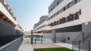 En modern byggnad med flera balkonger, en swimmingpool och en grön gräsyta.
