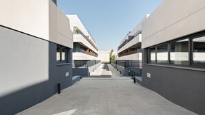 En modern byggnad med en central innergård, som kännetecknas av en symmetrisk design med balkonger och stora fönster.