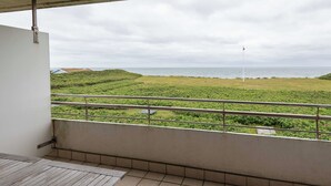 A balcony with a view of the sea and a grassy area. - 1-room apartment with sea view and approx. 34 m² living space, for up to 2 people (Wenningstedt-Braderup (Sylt))