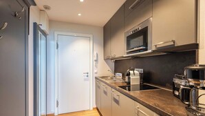 A modern kitchen with grey cabinets, a microwave, a coffee maker, and a toaster. - 1-room apartment with sea view and approx. 34 m² living space, for up to 2 people (Wenningstedt-Braderup (Sylt))