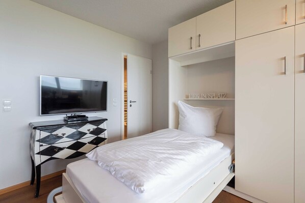 A bedroom with a bed, a TV, a dresser, and a wardrobe.