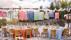 An outdoor dining area with multiple tables set for a meal, surrounded by stone walls and greenery. - Apartment with hot tub, A/C, WIFI, sauna, private pool, TV, patio, panoramic view, close to Siena (Monteriggioni)
