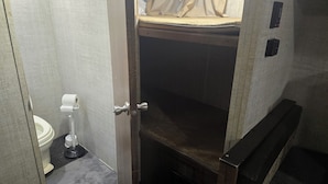 Un baño pequeño y estrecho con inodoro, lavamanos y zona de ducha.