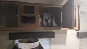 Una cocina con microondas, un mueble pequeño y una cesta sobre la encimera.